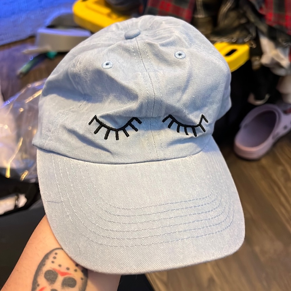 Light blue hat with closed eyes on the front